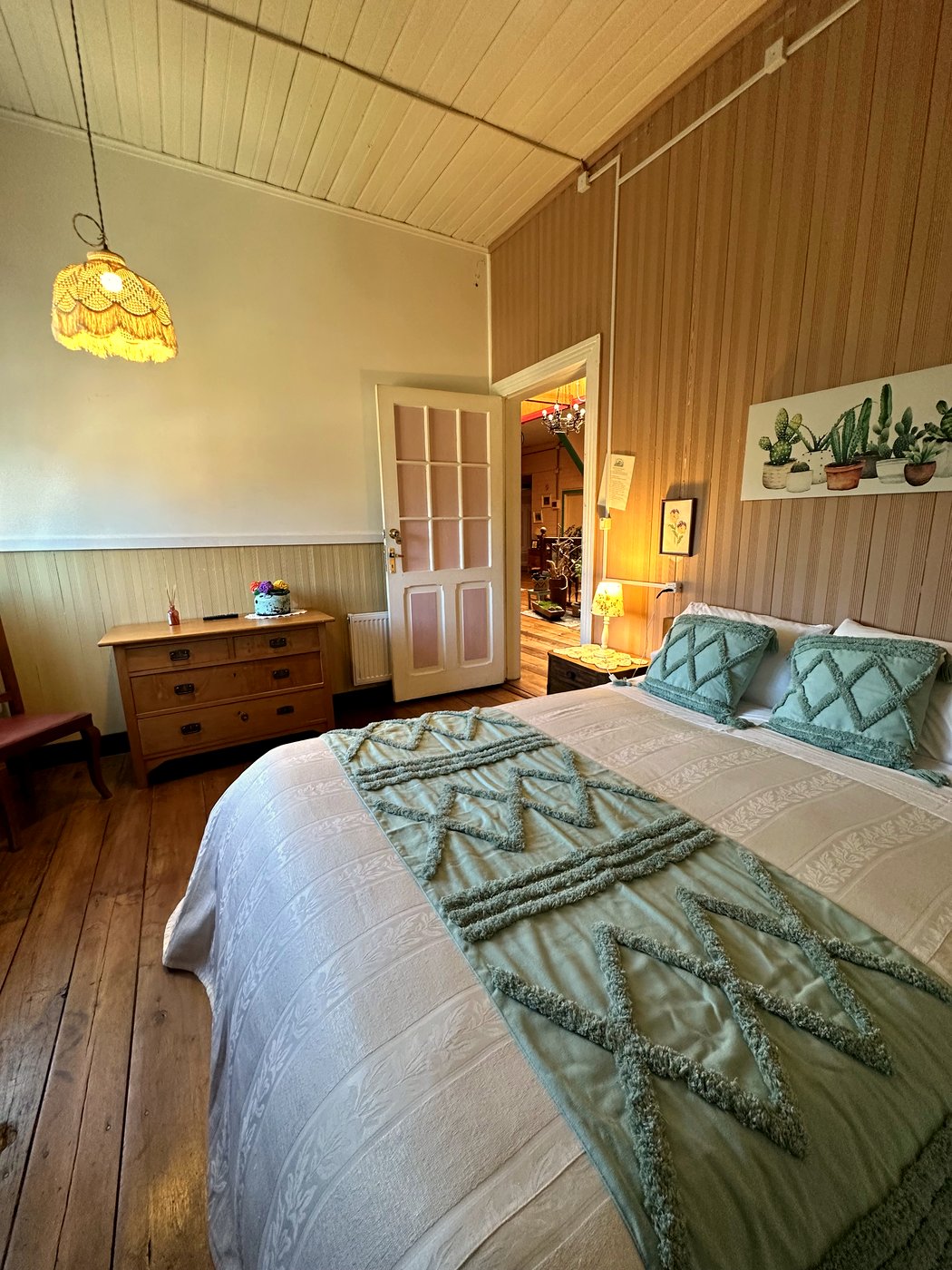 Habitación 2: buhardilla con techo inclinado, cama matrimonial con cubrecama verde salvia y baño privado en suite
